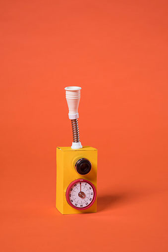 Boite en carton jaune avec un embout d'évier pour faire couler l'eau et un minuteur de cuisine, ready made des soeurs siamoises